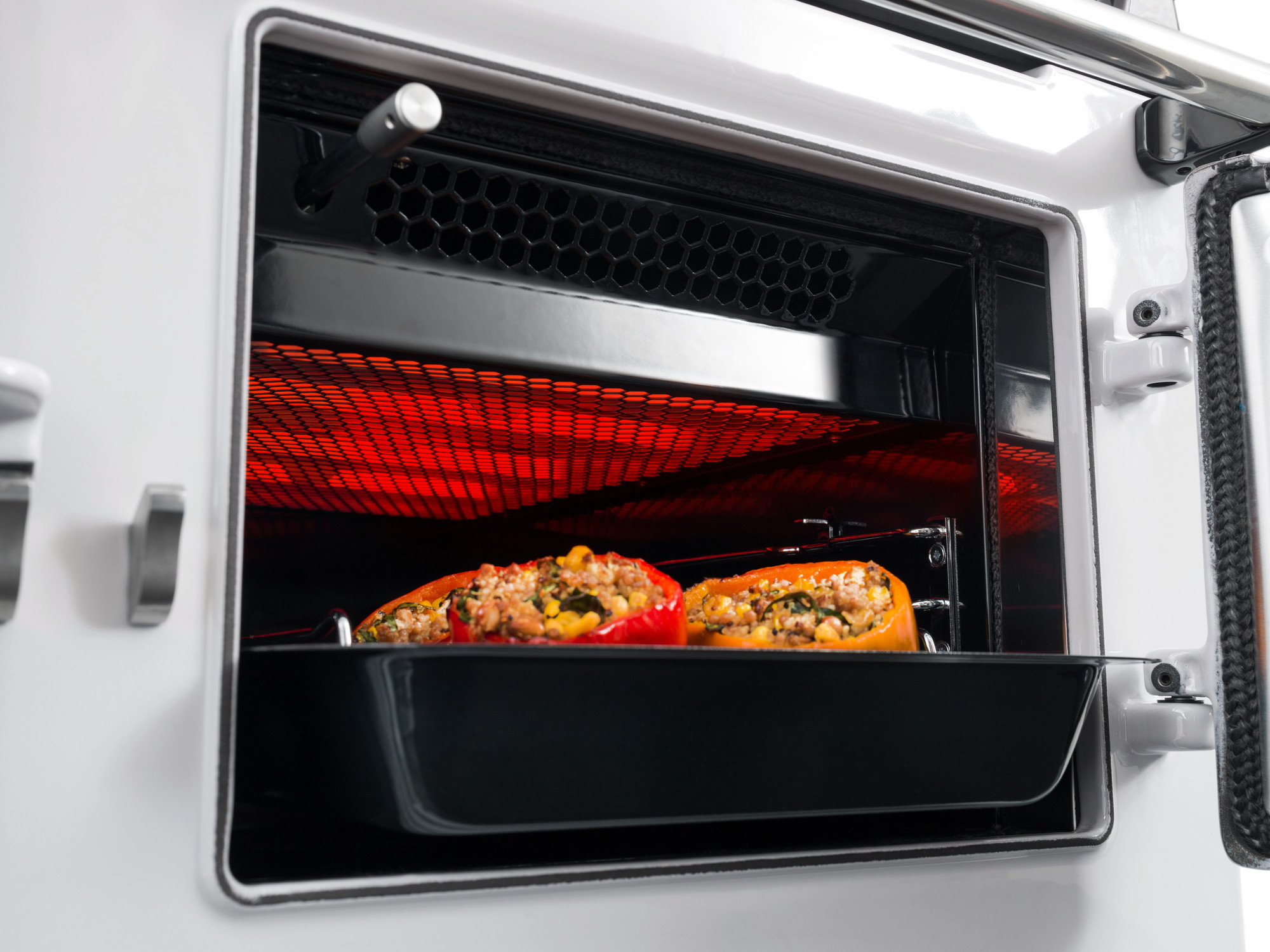 Frisch gefüllte Paprika mit Gemüse und Käse werden im Backofen in einer Backform unter einem eingeschalteten Grill gegart.