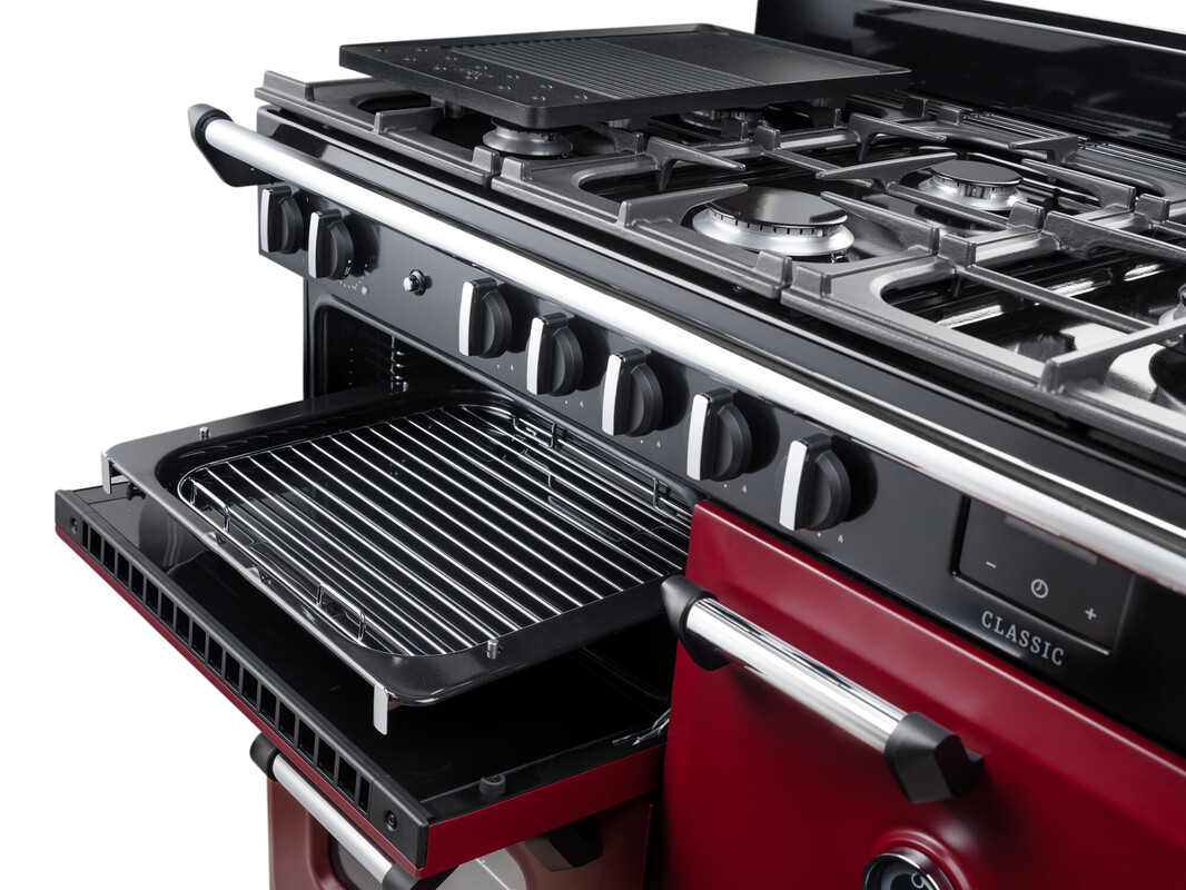 Detailansicht: roter Gas-Standherd (Range Cooker) mit 6-flammigem Kochfeld, gusseisernen Topfträgern, Griddle-Platte und geöffnetem Backofen mit herausziehbarer Grillpfanne – robustes Premium-Küchengerät